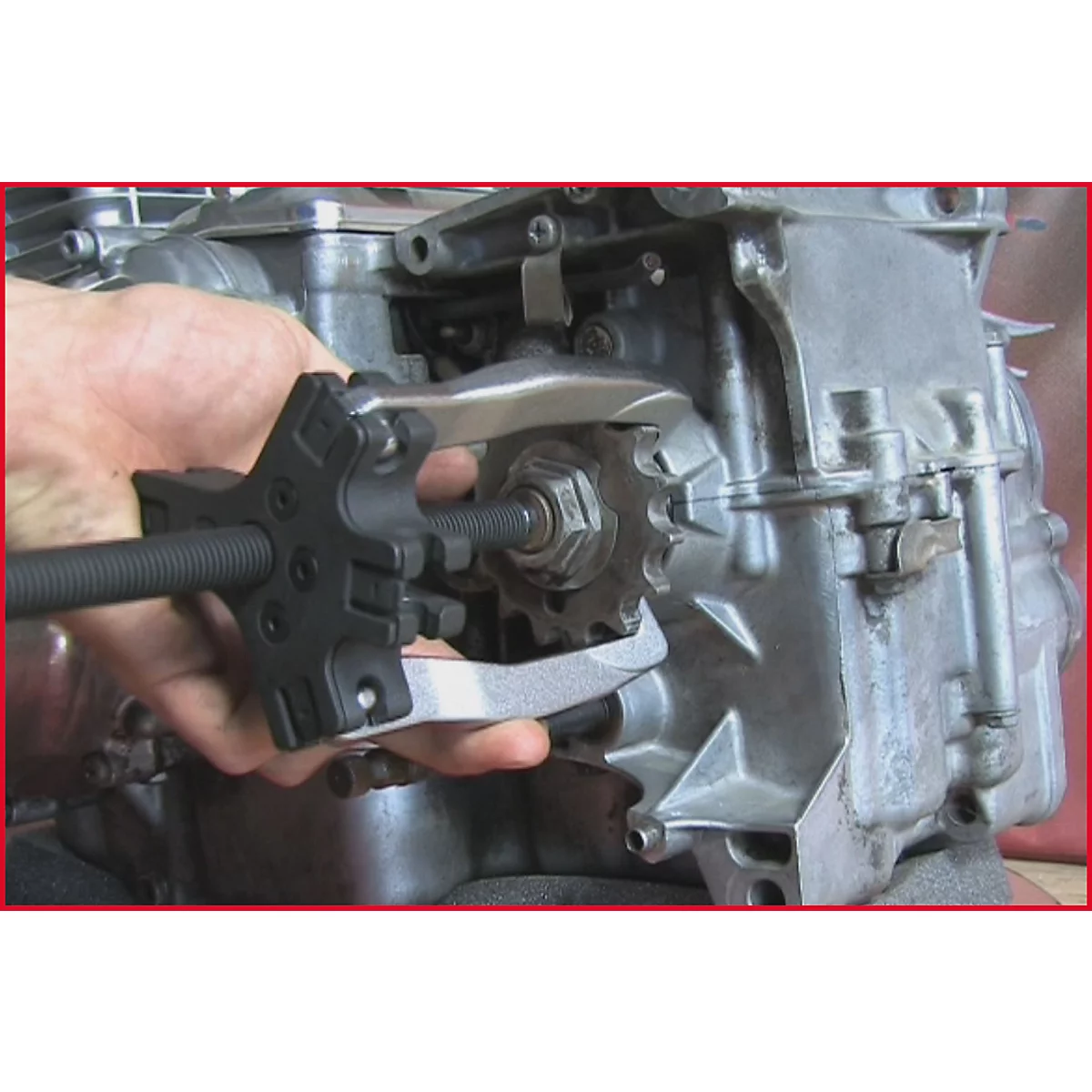 Hand hält Werkzeug zur Demontage von Komponenten eines Motors. Ein Zahnrad wird entfernt.